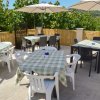 Terrazza all'aperto con tavoli apparecchiati, sedie bianche e nere, ombrelloni.