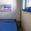 Una stanza con letto blu e un quadro di paesaggio marino sopra.