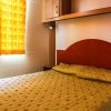 Una camera con letto ed elegante copriletto arancione a pois. Tende gialle filtrano la luce.