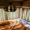 Interno di una roulotte con letto e lampadario.