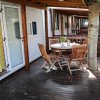 Terrazza in legno con tavolo rotondo e sedie, albero che attraversa il pavimento.