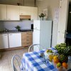 Cucina con tavolo apparecchiato e frutta, mobiletti bianchi e frigorifero.