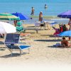 Spiaggia affollata con ombrelloni colorati e bagnanti in riva al mare.