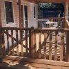 Una veranda in legno con ringhiere e sedie sotto una copertura.