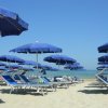 Spiaggia con ombrelloni e sdraio blu sotto il cielo sereno.