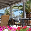 Sedie di vimini sotto una veranda con fiori e palme.