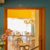 Ingresso di un ristorante con vista su tavoli e sedie, decorazioni floreali e un lampadario.