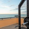 Vista del mare da una terrazza con attrezzature da palestra, inclusi pesi e bilancieri.