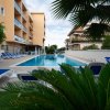 Piscina con lettini blu e palme attorno.
