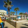 Spiaggia con palme, giochi per bambini e bandiere.