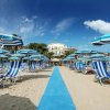 Spiaggia con sdraio e ombrelloni blu a righe.
