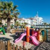 Area giochi per bambini sulla sabbia con palme.