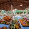 Una sala da pranzo all'aperto con tavoli apparecchiati e un buffet di frutta colorata.