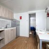 Interno di una cucina moderna con mobili in legno chiaro, tavolo da pranzo e grande finestra.