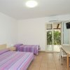 Camera con due letti singoli, arredi chiari, TV e porta finestra su veranda.