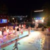 Serata all'aperto con bambini e adulti che ballano sotto luci colorate.