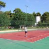 Persone giocano a tennis su un campo rosso.