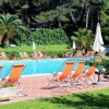 Piscina con sdraio arancioni e ombrelloni bianchi.