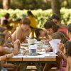 Bambini seduti a un tavolo all'aperto, impegnati in attività artistiche con pennarelli colorati.
