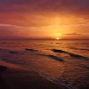 Tramonto sul mare con cielo arancione e onde leggere.