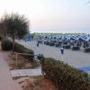 Sentiero accanto a una spiaggia con ombrelloni blu e bianchi all'alba; luci lungo il percorso.