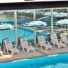 Lettini bianchi e ombrelloni a strisce blu e bianche accanto a una piscina.