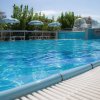 Piscina azzurra all'aperto con ombrelloni e lettini sullo sfondo.