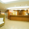 Area reception con divano in rattan e banco in legno.