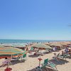 Spiaggia sabbiosa con ombrelloni colorati e mare calmo.