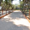 Un campo da bocce recintato tra alberi con panchine ai lati.