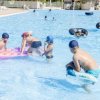 Bambini che giocano in piscina con materassini e ciambelle gonfiabili.