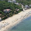 Vista aerea di una spiaggia con ombrelloni e vegetazione.