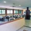 Sala da pranzo luminosa con tavoli apparecchiati, pareti vetrate e pavimento piastrellato.