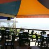 Ristorante all'aperto con tavoli e sedie, vista sul mare.
