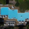 Piscina rettangolare azzurra vista dall'alto, circondata da lettini bianchi sotto ombrelloni.