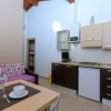 Cucina moderna con mobiletti chiari e scuri, tavolo apparecchiato e divano con cuscini colorati.