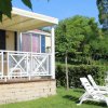 Veranda di una casa mobile con sedie a sdraio su un prato verde.