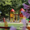 Parco giochi colorato con giostre su erba e alberi intorno.