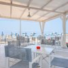 Terrazza con tavoli, sedie e vista mare e ombrelloni.