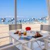 Tavolo all'aperto con colazione vista mare e ombrelloni blu in spiaggia.
