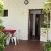 Una veranda con tavolo e sedie bianche, circondata da piante verdi.