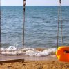Altalene sulla spiaggia con mare sullo sfondo.