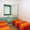 Camera con due letti singoli, coperte arancioni, una finestra e un comodino centrale.