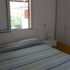 Camera da letto con un letto a righe blu e armadio bianco, finestra aperta.