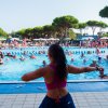 Persona insegna aerobica a bordo piscina affollata.