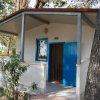 Bungalow bianco con porta blu in un bosco.