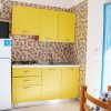 Cucina con mobili gialli, frigorifero e tavolo.
