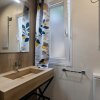 Bagno moderno con lavandino in legno e tende floreali.