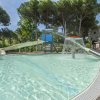 Piscina con scivolo, spruzzi d'acqua e sedie a sdraio.