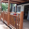 Veranda in legno con ringhiera e accesso a una casa mobile.
